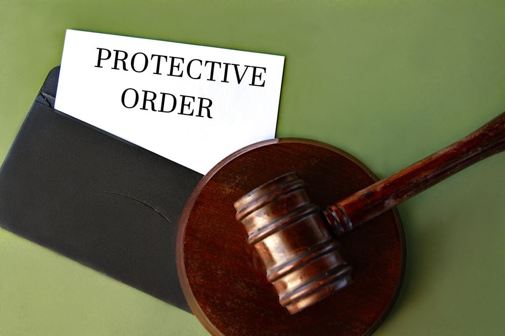 Black envelope with the text PROTECTIVE ORDER and the judge's gavel on a green background
